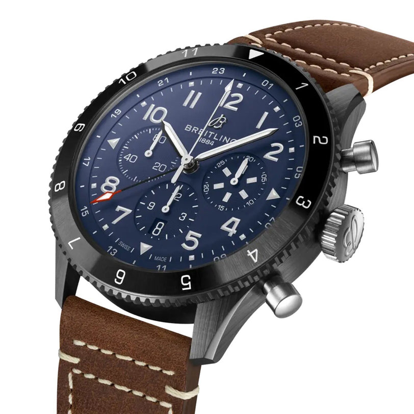 The Breitling Super AVI B04 Chronograph GMT 46 Tribute To Vought F4U features a blue dial, three subdials, black bezel, silver pushers, and a brown leather strap with white stitching—an aviation-inspired pilot’s watch.