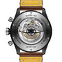 Close-up of the back of the Breitling Super AVI B04 Chronograph GMT 46 Tribute To Vought F4U, revealing its mechanical movement and aviation-themed engravings, paired with a yellow leather strap.