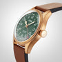 A close-up of the Oris Big Crown Pointer Date 80th Anniversary Edition highlights its green dial, bronze case, textured brown leather strap, and prominent crown, with the time set at 10:08.