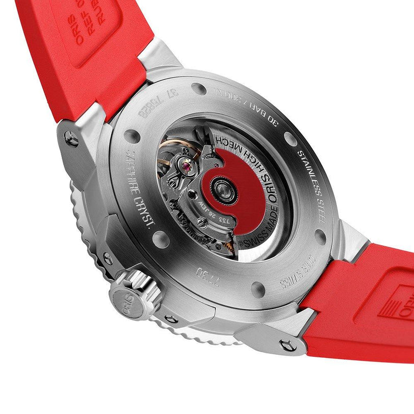 Close-up of the Oris Aquis Date Relief’s stainless steel case back, featuring an automatic movement visible through a transparent window and paired with a vivid red rubber strap.