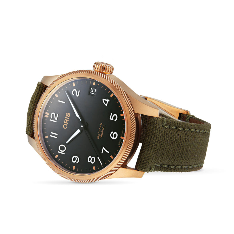 The Oris Big Crown ProPilot Big Date wristwatch, featuring a bronze case, black dial with white numerals, and olive green fabric strap, is shown at an angle on a white background.