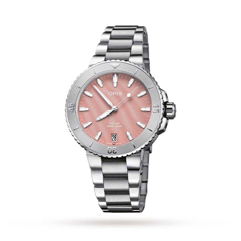 The Oris Aquis Date, a stainless steel divers watch, features a blush pink dial with silver hour markers, a 6 o’clock date display, and is presented on a metal link bracelet against a white background.