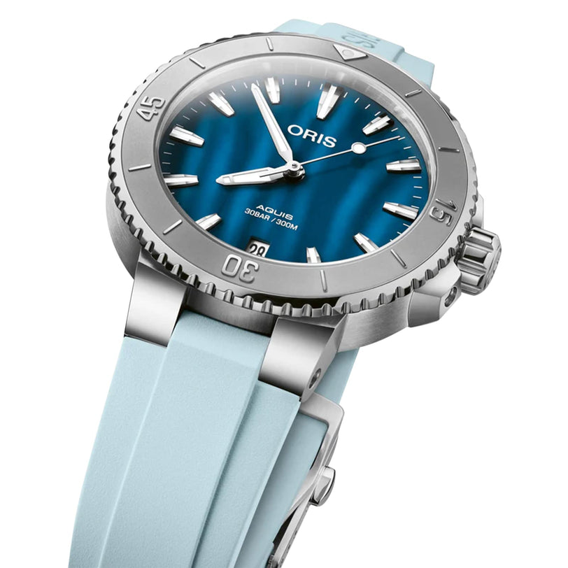 The Oris Aquis Date is a high-performance diver’s watch in stainless steel, featuring a blue dial with silver markers, light blue rubber strap, and a rotating bezel.