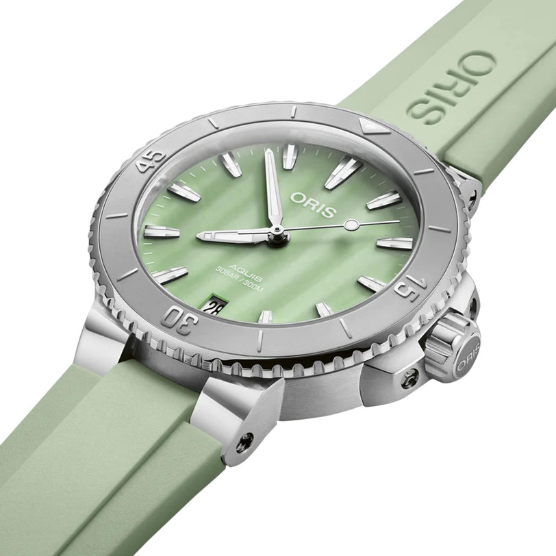 The Oris Aquis Date watch in mint green features a matching strap and silver bezel, displayed at an angle.