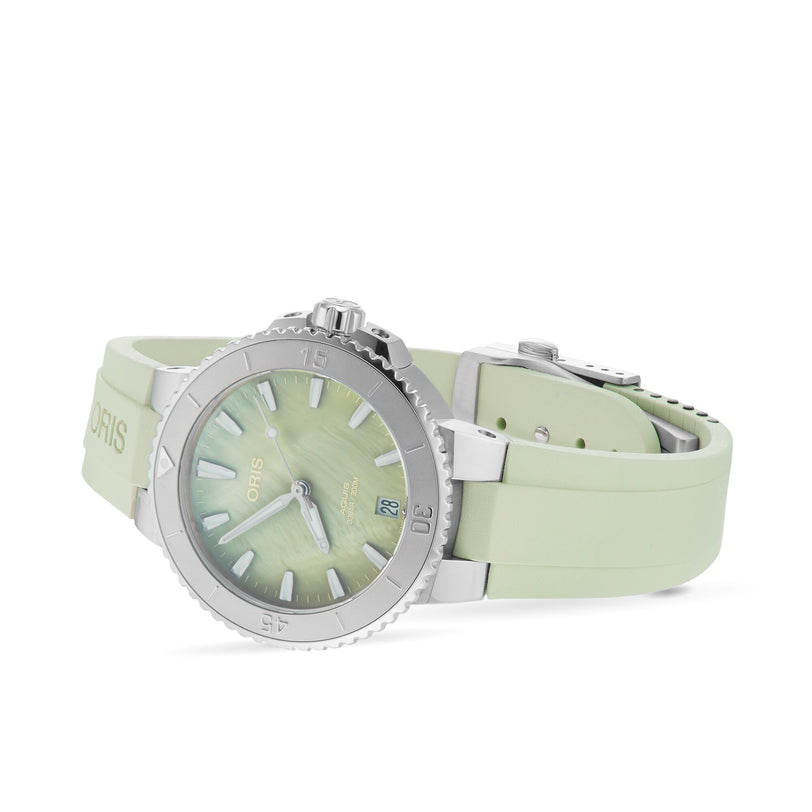 An Oris Aquis Date wristwatch with a silver case, pale green dial, and matching rubber strap is angled on a white background.