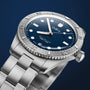 The Oris LFP Limited Edition is a stainless steel wristwatch with a blue dial, rotating bezel, and metal bracelet, shown against a dark blue background—created to celebrate the Ligue de Football Professionnel.