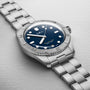 An Oris LFP Limited Edition wristwatch with a blue dial and metal link bracelet displayed on a light textured surface.