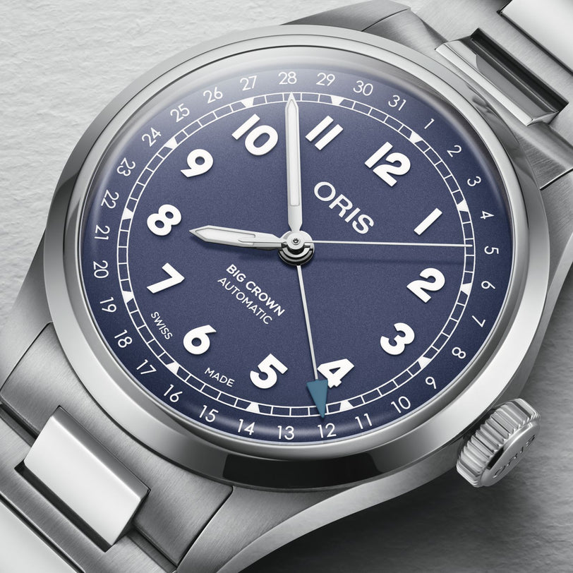 A close-up of the Oris Big Crown Pointer Date watch, featuring a blue dial, automatic movement, white numerals, and a stainless steel bracelet, displaying the time at 10:10:37.