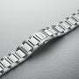 A brushed stainless steel bracelet with an ORIS-engraved clasp, part of the Oris Big Crown Pointer Date Calibre 403, exemplifies Swiss watchmaking and is shown on a light textured surface.