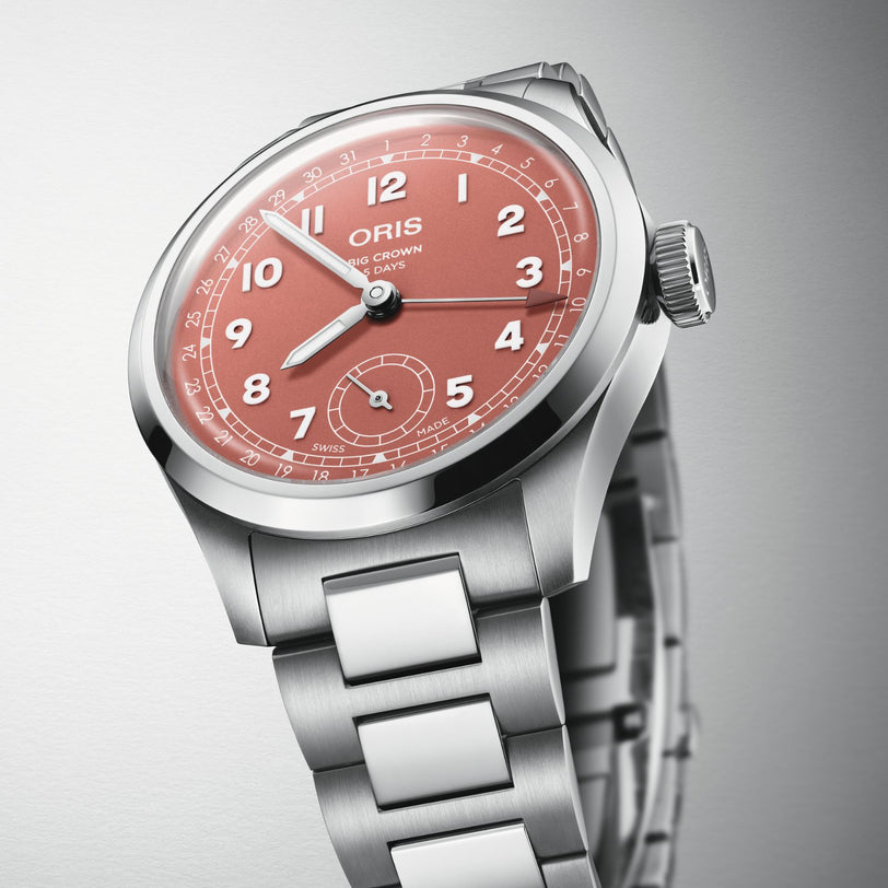 The Oris Big Crown Pointer Date Calibre 403 features a stainless steel case, salmon dial with white numerals and date track, a subdial at 6 o’clock, and comes on a metal bracelet.