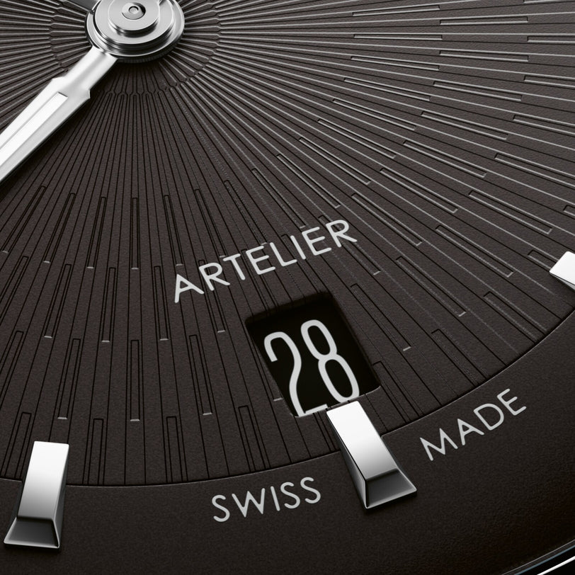 Black dial watch face with radial line pattern, showing date window at 28, Artelier branding, and Swiss Made text, with silve