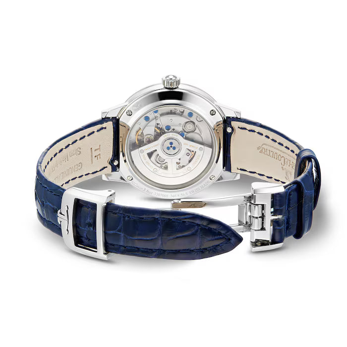 The Jaeger-LeCoultre Rendez-Vous Night & Day is a luxury women's watch featuring a visible mechanical movement, silver case, dark blue leather strap with white stitching and deployment clasp, and a light beige inner side.