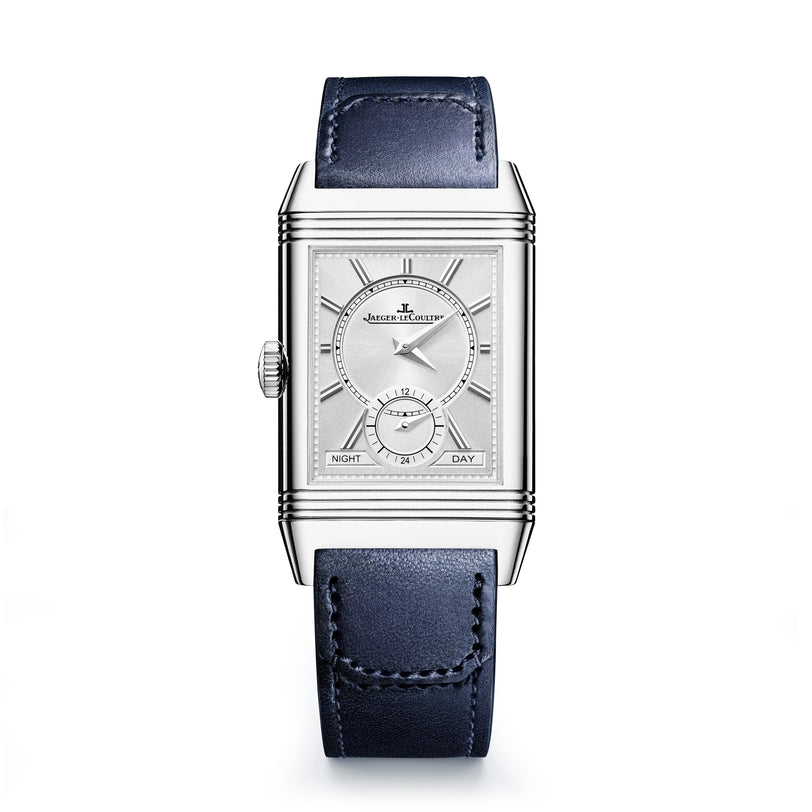The Jaeger-LeCoultre Reverso Tribute Duoface Small Seconds is an Art Deco-style rectangular silver wristwatch with a white dial, day/night indicator, blue leather strap, and Duoface complication, shown on a white background.