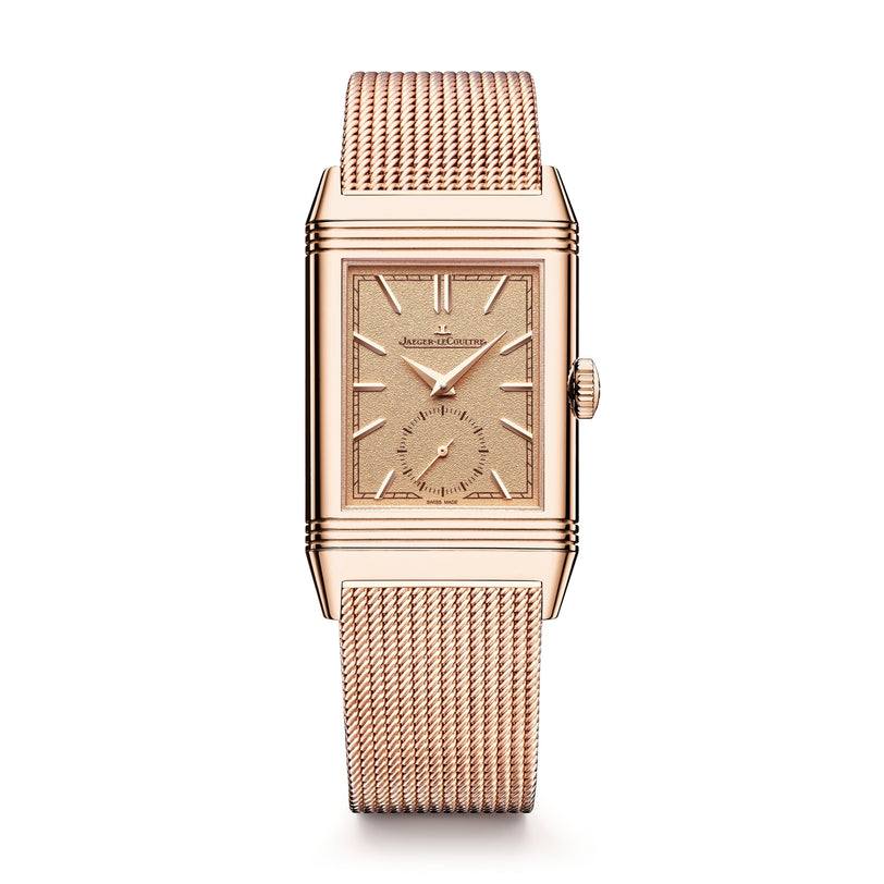 The Jaeger-LeCoultre Reverso Tribute Monoface Small Seconds is a rectangular rose gold wristwatch with a mesh band, golden grained dial, minimalist display, and small seconds subdial, shown against a white background.