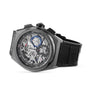 The Zenith Defy El Primero 21 is a luxury skeleton watch with a black leather strap, black bezel, visible gears, and urban design elements accented in blue, red, and white on the dial.