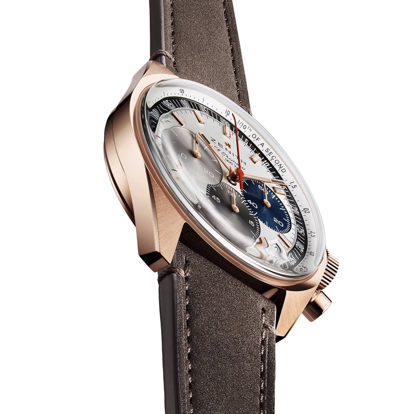 A close-up side view of the Zenith Chronomaster EP Original watch, showcasing its mechanical calibre, brown leather strap, rose gold case, and detailed dial with chronograph subdials and orange accents.