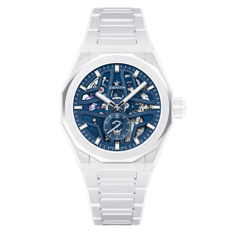 The Zenith Defy Skyline Skeleton White Ceramic wristwatch features a blue skeleton dial with visible gears, El Primero 3620 SK movement, a metal link bracelet, and an interchangeable strap, shown on a white background.