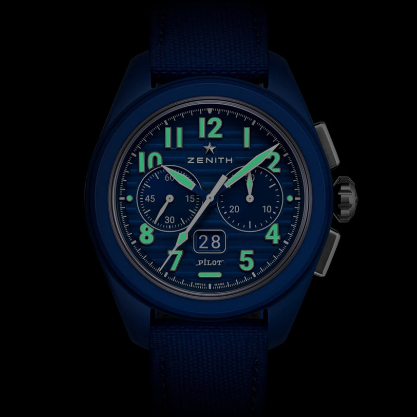 The Zenith Limited Edition Pilot Big Date Flyback 160th Anniversary wristwatch features a blue dial, luminous hands and numerals, two subdials, a date window at 6 o’clock, and a fabric strap, displayed on a black background.