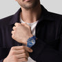 A person in a navy jacket and white shirt showcases the Zenith Limited Edition Chronomaster Sport 160th Anniversary Edition on their left wrist, adjusting the watch with their right hand.