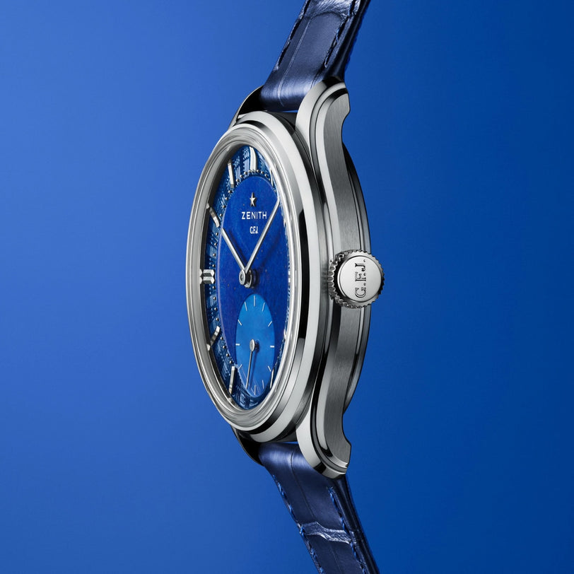 The Zenith Limited Edition G.F.J. Calibre 135 160th Anniversary Edition boasts a platinum round case, blue dial, and blue leather strap, displayed elegantly against a matching blue background.
