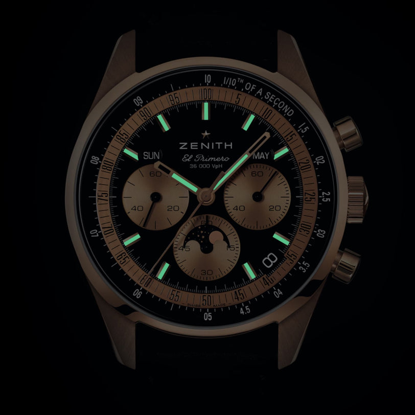 The Zenith Chronomaster Original features gold details, three subdials, and luminous green hour markers set against a dark dial.