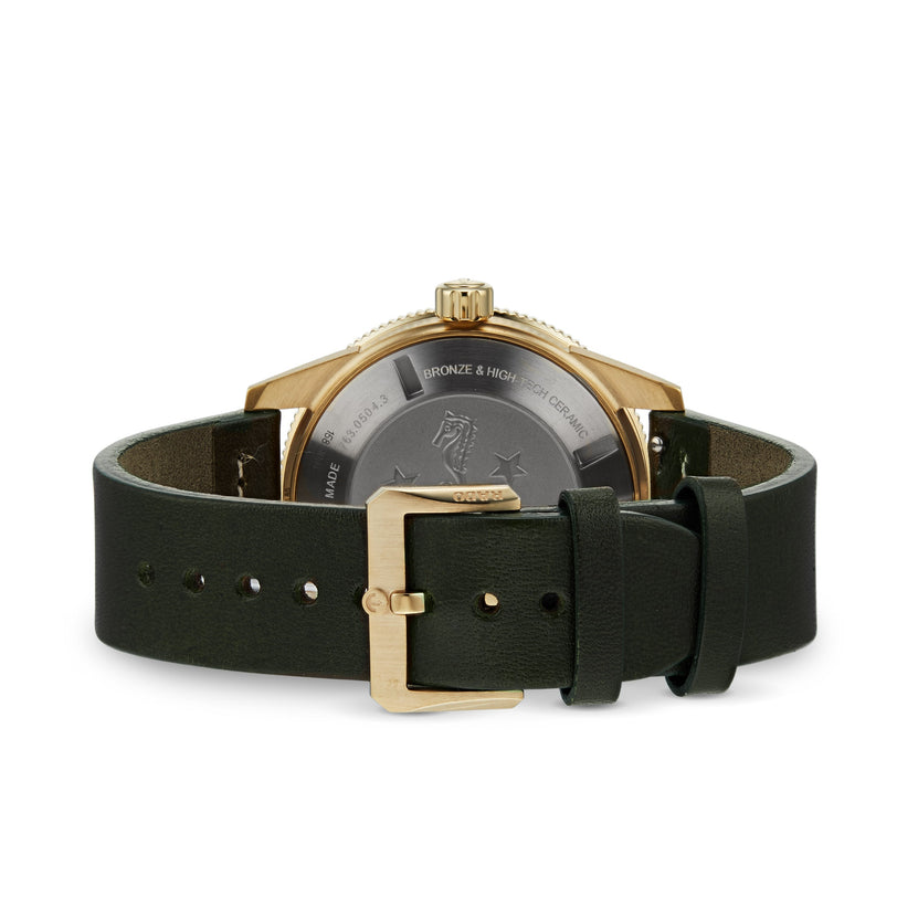 A close-up of the Rado Captain Cook Automatic Bronze wristwatch, featuring a green leather strap, gold buckle, and steel case back with engraved text—blending vintage charm and modern elegance.