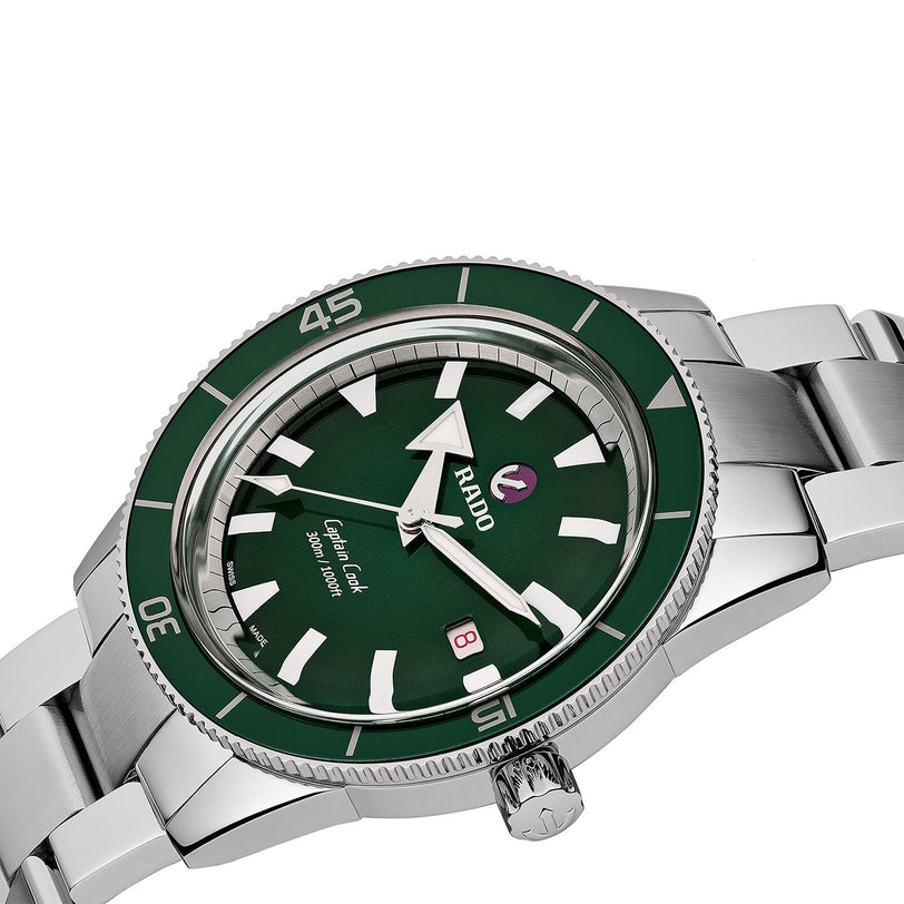 The Rado Captain Cook Automatic is a stainless steel wristwatch with a green bezel and dial, vintage details, white hour markers, date window at 3 o’clock, and water resistance.