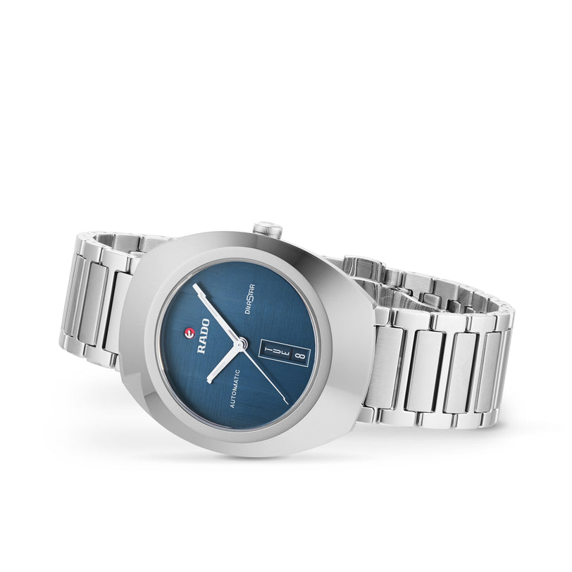A silver metal Rado DiaStar Original wristwatch with a blue dial, date display, and sapphire crystal is shown on a white background.
