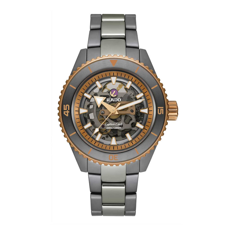The Rado Captain Cook High-Tech Ceramic Skeleton watch features a metal bracelet, skeleton dial, and gold-tone accents on the bezel and crown, powered by the precise R808 movement and shown against a white background.