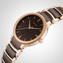 The Rado Centrix is a luxury gold and black automatic watch with a black dial, minimal hour markers, date display, and a two-tone bracelet, elegantly set against a light gray background.
