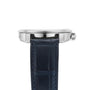 Side view of the Ulysse Nardin Marine Torpilleur, featuring a silver case with a ridged bezel, textured crown, and a dark blue stitched leather strap.