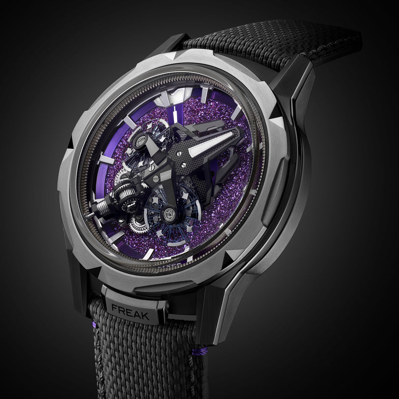 A close-up of the Ulysse Nardin Freak S WOS Centenary Exclusive, featuring its detailed exposed mechanical movement and black strap, set against a purple textured background signature to the brand.