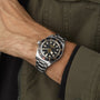 Wrist wearing the TUDOR Black Bay 58 with a green khaki jacket