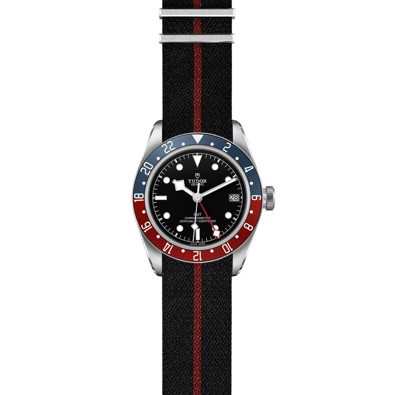 The TUDOR Black Bay GMT features a black dial, red and blue bezel, and a black fabric strap with a bold red stripe—an iconic diving watch.