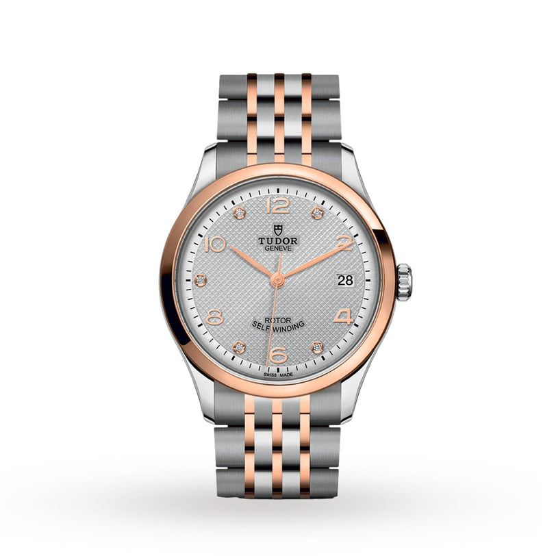 The TUDOR 1926 features a silver and rose gold two-tone metal band, white textured dial, gold hour markers, date window at 3 o’clock, and a scratch-resistant sapphire crystal lens.