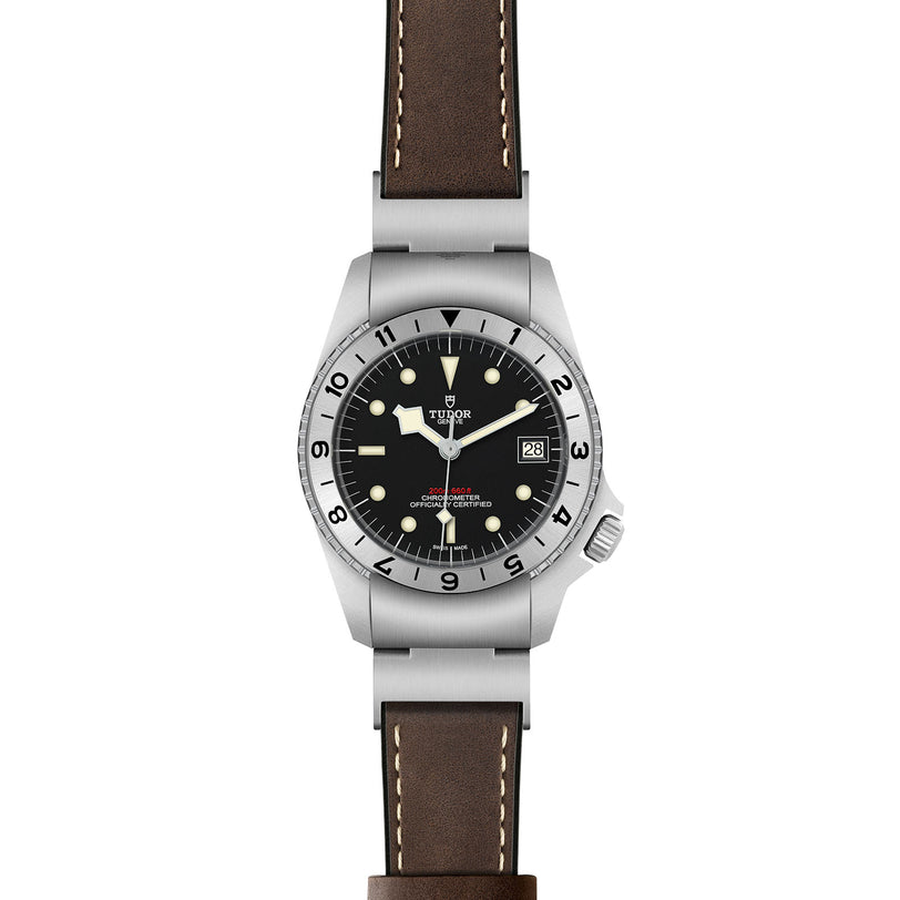 The TUDOR Black Bay P01 is a stainless steel wristwatch featuring a black dial, snowflake hands, white hour markers, a date window at 3 o’clock, and a brown leather strap.