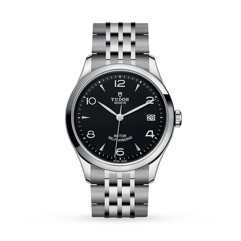 The TUDOR 1926 is a classic stainless steel wristwatch featuring a black textured dial, silver hour markers, date at 3 o’clock, and a five-link metal bracelet, highlighting the timeless appeal of mechanical watches against a white background.