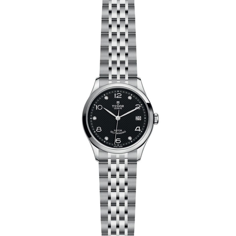 A TUDOR 1926 stainless steel wristwatch featuring a black dial, silver hour markers, a date window at 3 oclock, and a metal link bracelet is displayed against a white background—a classic example of TUDOR craftsmanship.