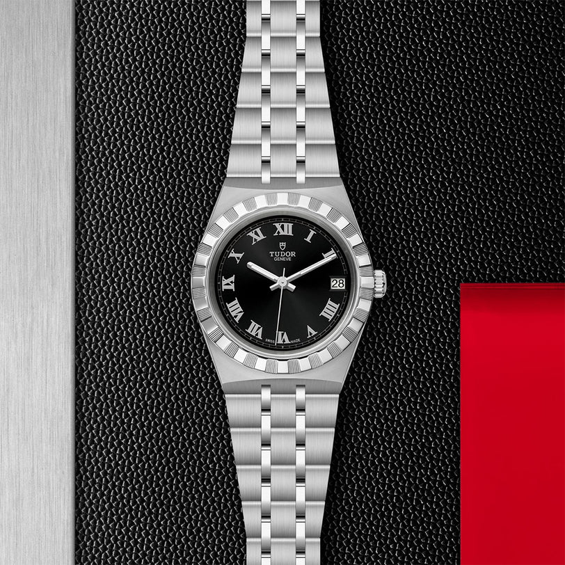 The TUDOR Royal wristwatch features a black dial, Roman numerals, date window, and a metal link bracelet. Displayed on a textured black background, it embodies the refined elegance of sport-chic design.