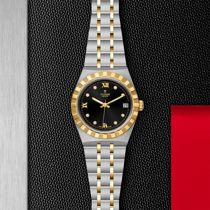 The TUDOR Royal features a black dial with gold Roman numerals and a date display at 3 o’clock, highlighted against a textured black and metallic background—embodying the sport-chic style and technical excellence of TUDOR.