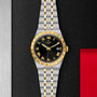 The TUDOR Royal wristwatch features a black dial with gold Roman numerals, a date window, and an integrated bracelet, showcased against a textured black and metallic background.