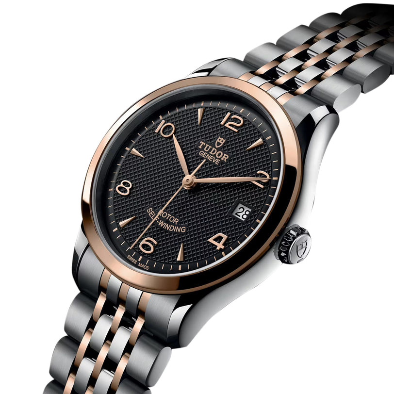 The TUDOR 1926 is a mechanical watch with a black textured dial, gold hour markers, date display, and a two-tone silver and gold metal bracelet.
