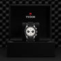 A TUDOR Black Bay Chrono wristwatch with a black strap and white dial is shown in an open black TUDOR box against a textured black backdrop, highlighting its signature tachymetric scale.