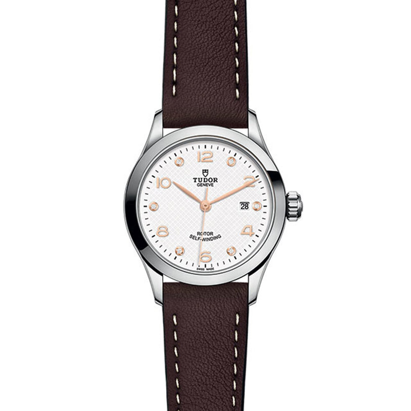 A classic, elegant timepiece, the TUDOR 1926 features a white dial, rose gold markers, date window at 3 o’clock, and a brown leather strap with white stitching—a timeless design from TUDOR.