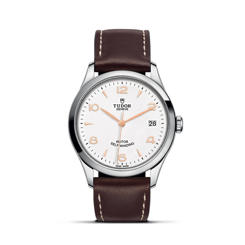 The TUDOR 1926 features a white textured dial, brown leather strap, silver case, gold-tone markers, date at 3 o’clock, and ROTOR SELF-WINDING text—a classic elegant wristwatch.