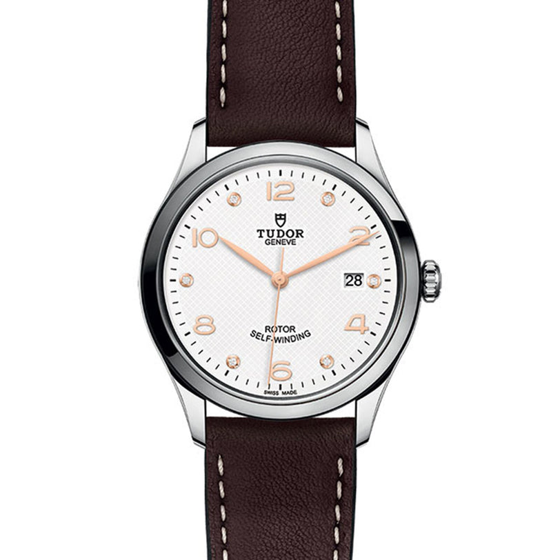 The TUDOR 1926 wristwatch boasts an elegant white dial, gold-tone hour markers, date window at 3 o’clock, and a brown leather strap—a refined choice from TUDOR.