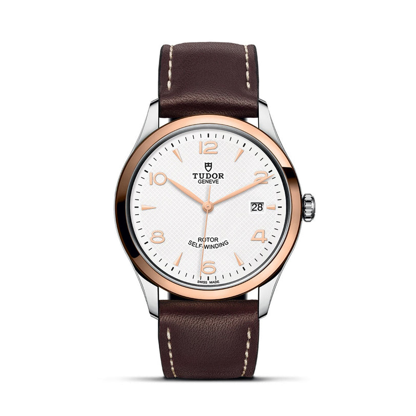 The TUDOR 1926 features a white dial, gold bezel, brown leather strap, and date display at 3 o’clock—a refined mechanical wristwatch showcased on a white background.