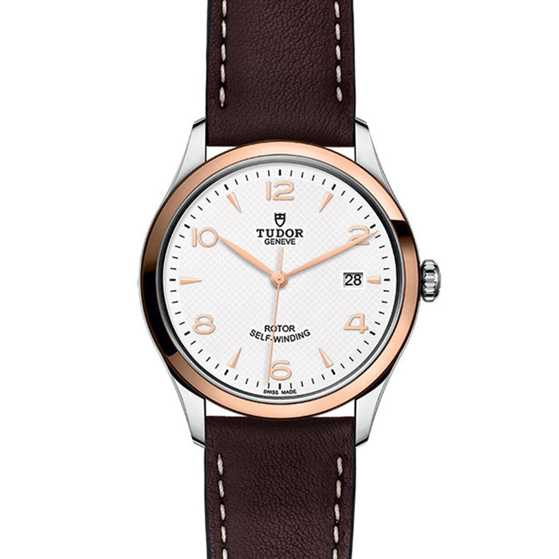 The TUDOR 1926 features a white dial, rose gold bezel, brown leather strap, and date at 3 o’clock. Marked Rotor Self-Winding and Swiss Made, it’s a classic mechanical watch choice.