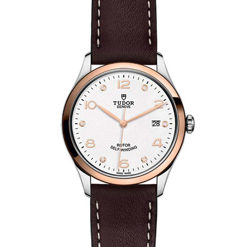 The TUDOR 1926 is a wristwatch featuring a white dial, brown leather strap, gold-tone markers, and a date display.