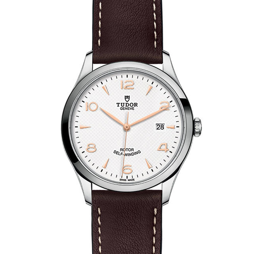 A TUDOR 1926 wristwatch featuring a white dial, brown leather strap, silver case, date display at 3 o’clock, and gold hour markers and hands.